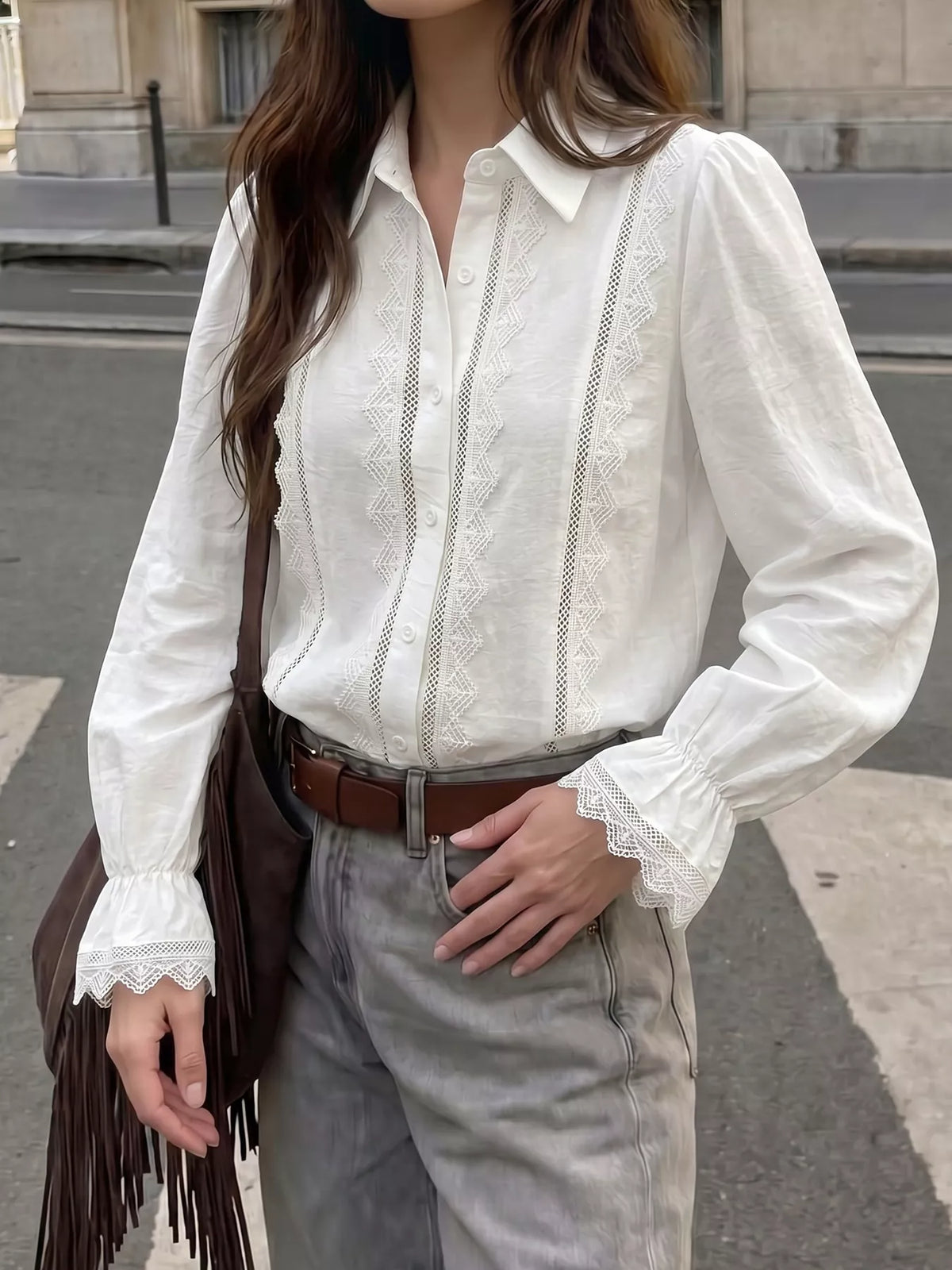 Drei-Viertel-Ansicht weißes Shirt in graue Jeans gesteckt, zeigt geometrische Spitzenpanels und ausgestellte Ärmelenden.