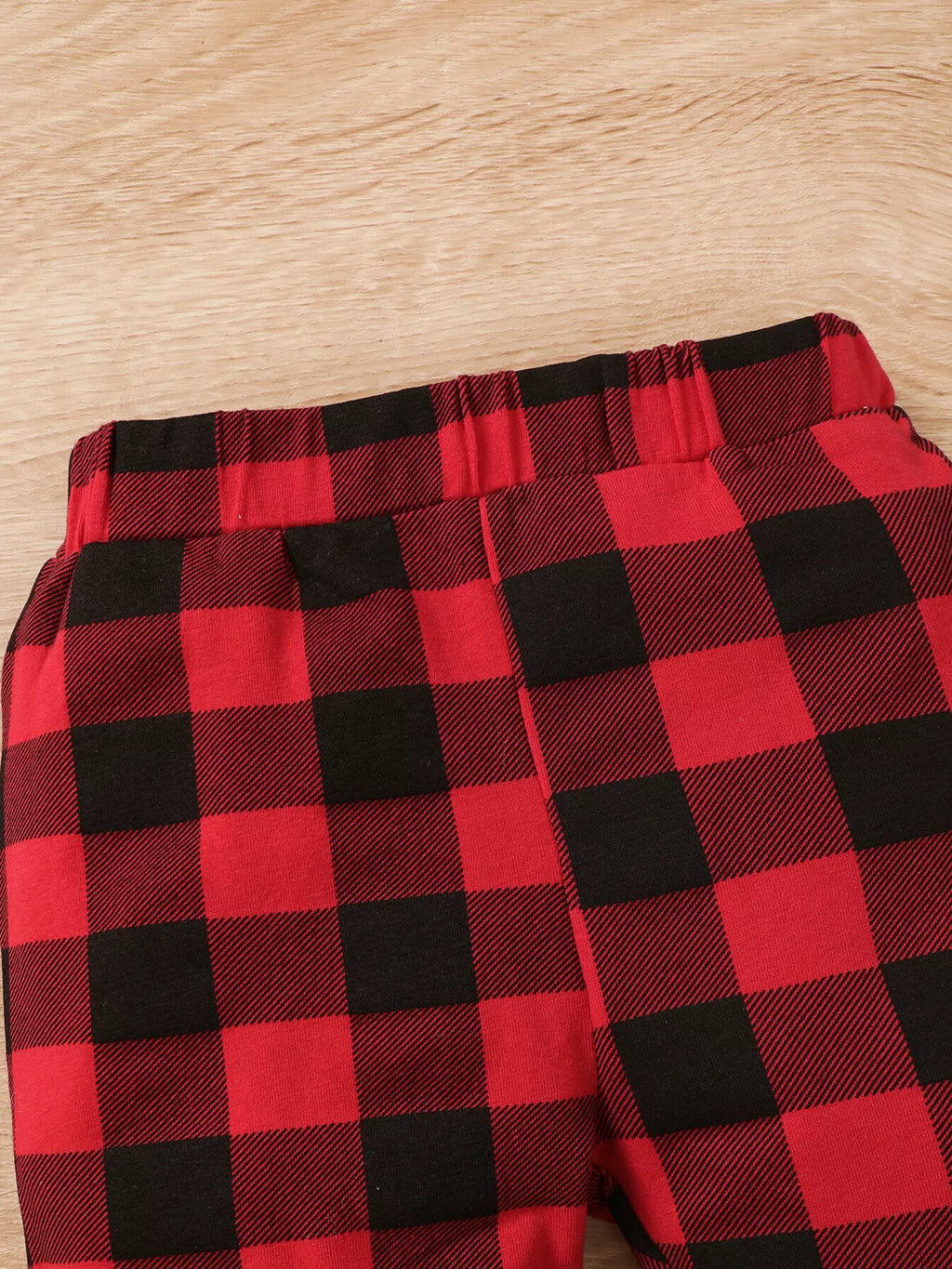 Cintura elástica de los pantalones a cuadros rojo y negro mostrando construcción recogida y patrón de poliéster elastano a cuadros