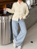 Modell lehnt an der Theke und zeigt die lockere Passform der cremefarbenen gestreiften Jacke