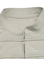 Détail du col mandarin haut et de la patte de boutonnage zippée argentée sur vêtement extérieur beige clair