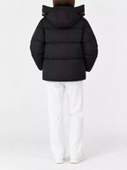 Back view of model in black quilted hooded puffer jacket with horizontal stitching and white pants