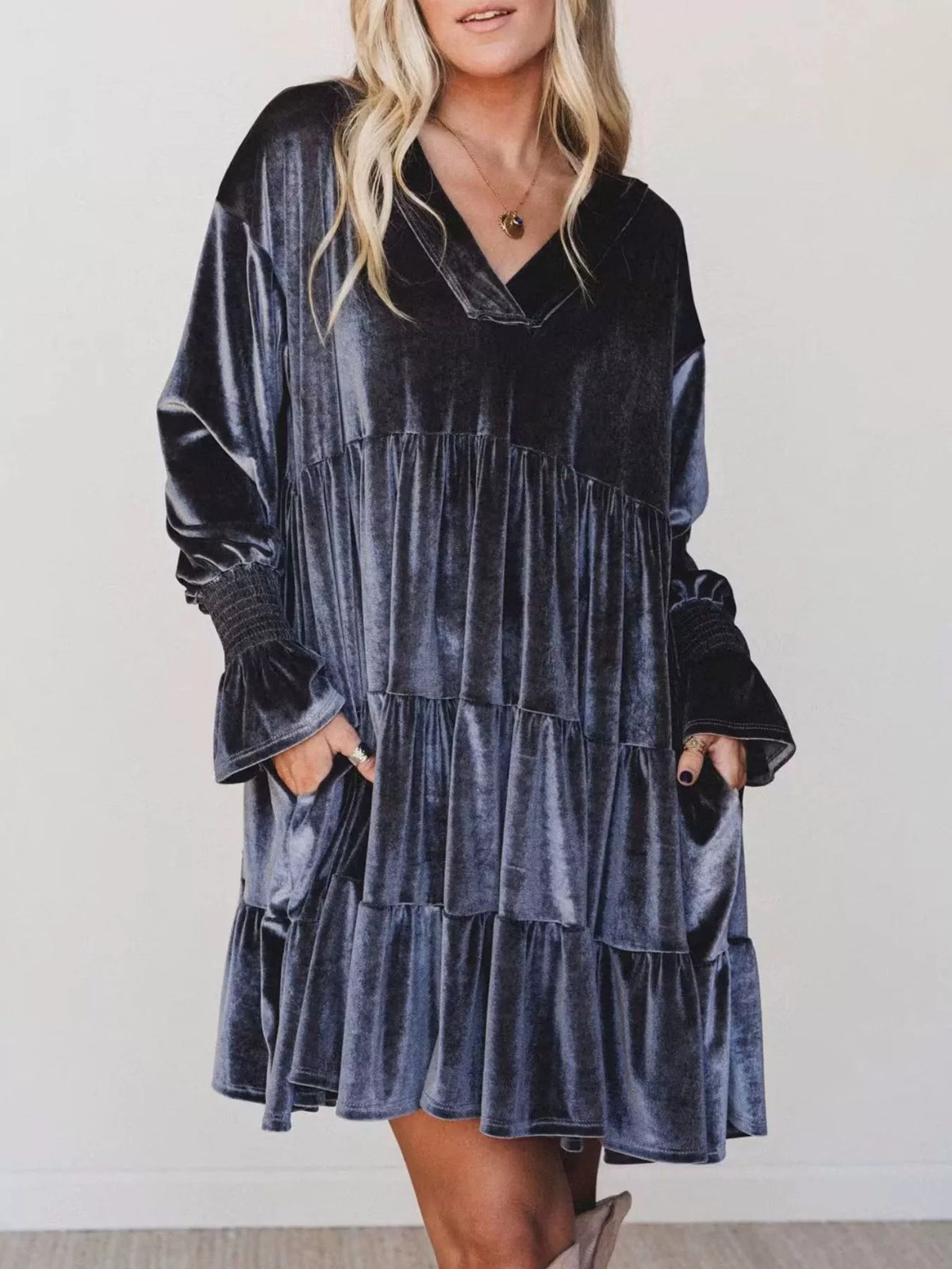 Vista frontale di una mini dress in velluto blu scuro con scollo a V, volant a livelli, maniche voluminose e tasche laterali