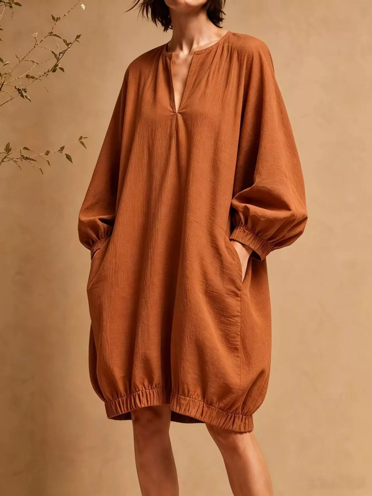 Vista frontal del vestido mini naranja óxido mostrando silueta A, mangas globo y dobladillo elástico