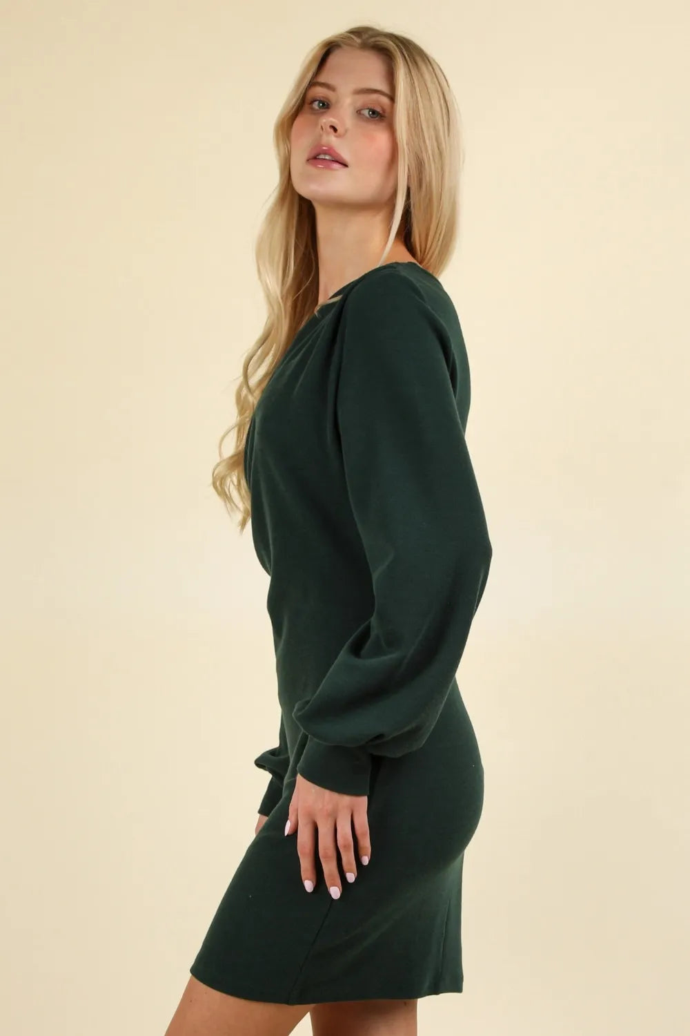 Side profile of dark green mini dress highlighting curve-hugging fit