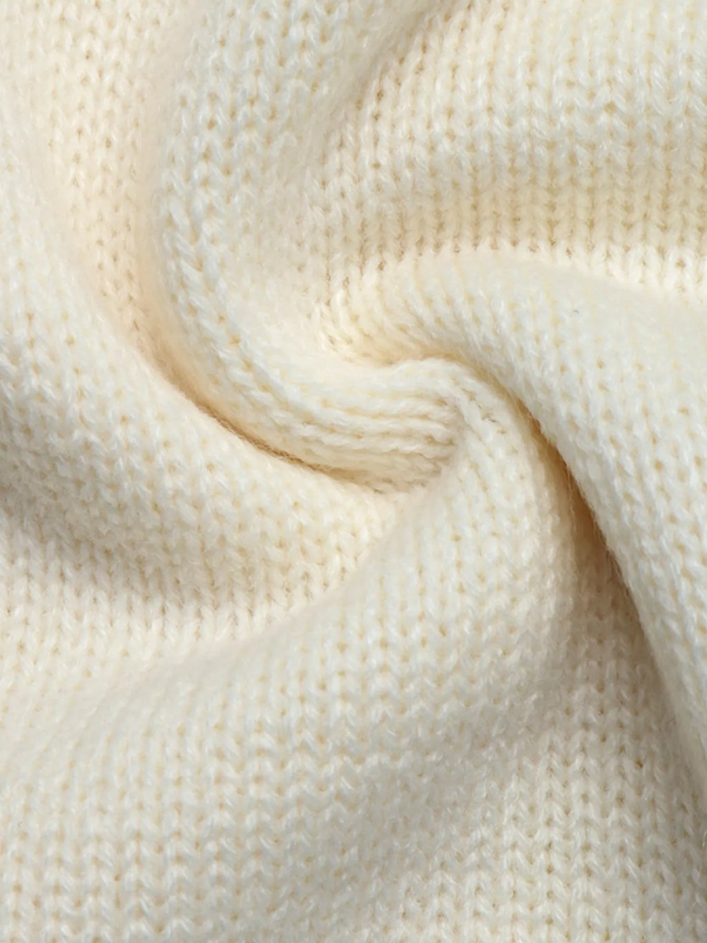 Makroaufnahme der weichen, feinmaschigen Textur und der gedrehten Garne der cremefarbenen Strickware