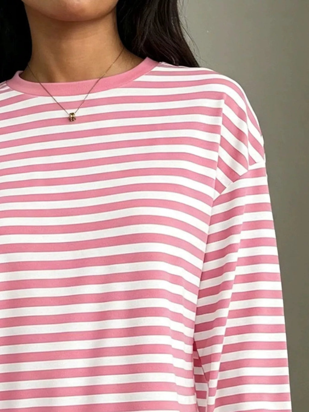 Detail of pink and white striped t-shirt upper chest highlighting even stripe pattern, ribbed binding, and smooth polyester