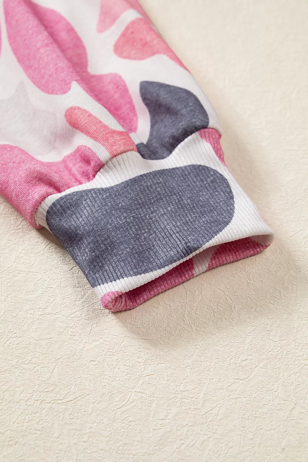 Ribbed elastic sleeve cuff detail showcasing stretchy knit texture against beige background