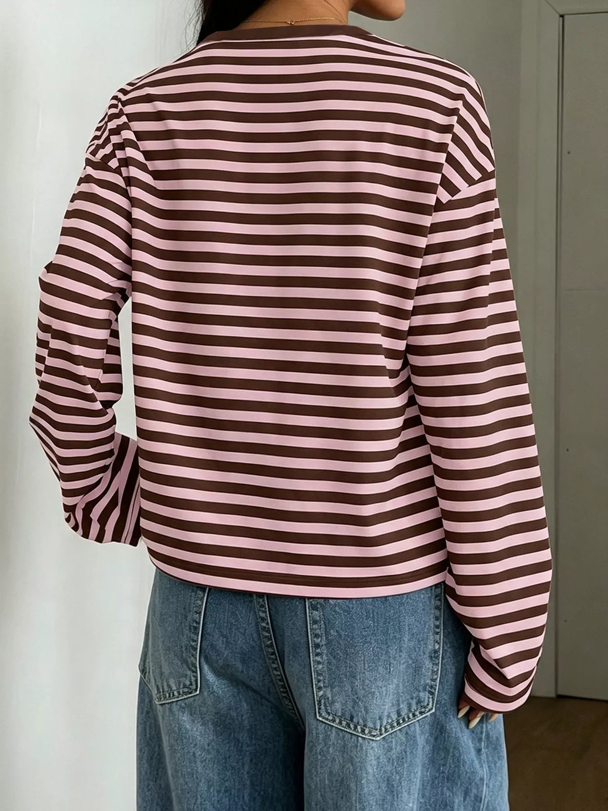Back view of brown and dusty pink striped t-shirt showing continuous horizontal stripes across back and dropped shoulder seam