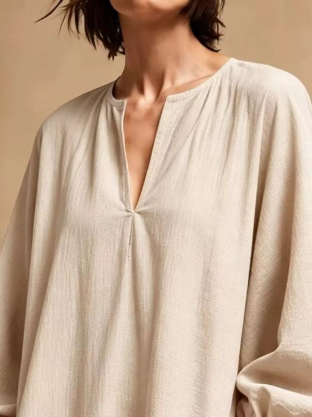 Détail du col de la robe beige avec texture polyester douce, col rond avec encolure en V et plis centraux