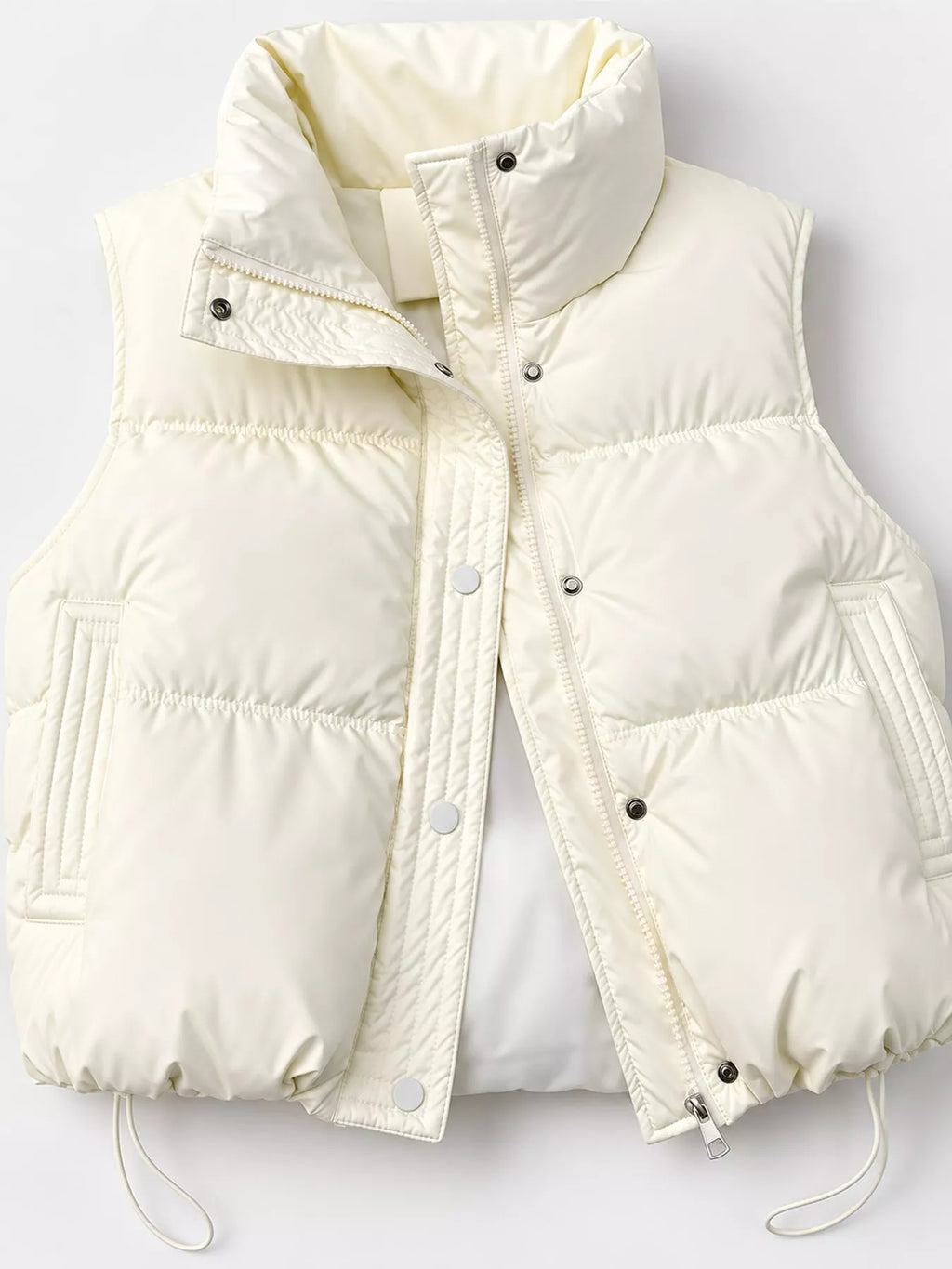 Close-up of cream vest hardware showing silver snaps, zipper, and polyester texture