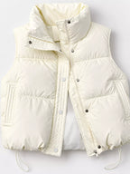 Close-up of cream vest hardware showing silver snaps, zipper, and polyester texture