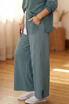 Seitendetail der teal Hose mit weißem Quasten-Kordelzug, Patch-Tasche und Knöchelschlitz über Sneakers