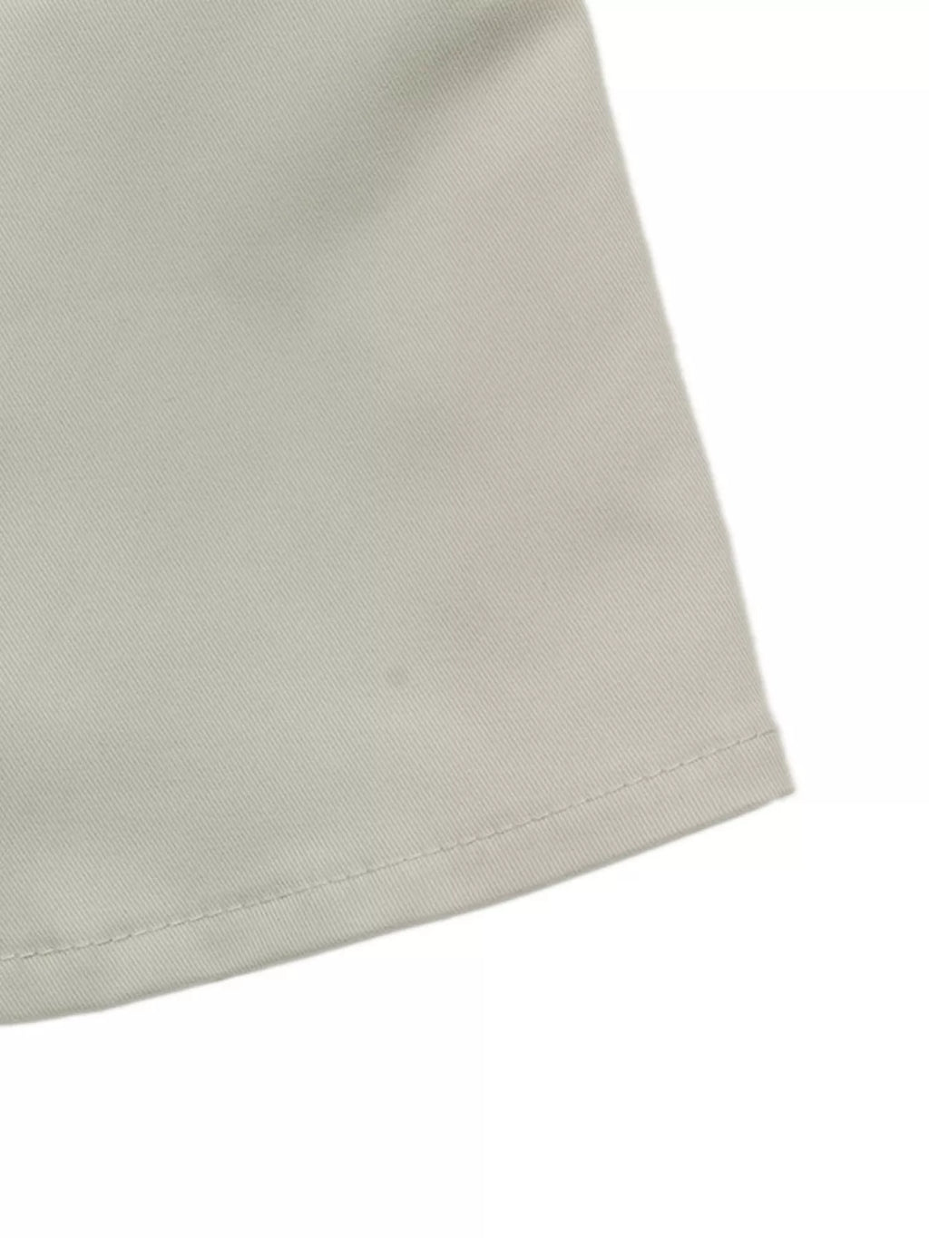 Détail de l'ourlet inférieur montrant une couture droite nette sur le matériau de veste beige uni
