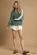 Sage green oversized sweatshirt with white sleeve stripes worn by a model in cream shorts