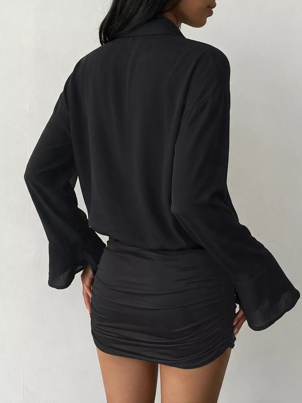 Angle arrière robe-shirt noire : panneau dos lisse et manches fluides contrastant les fronces
