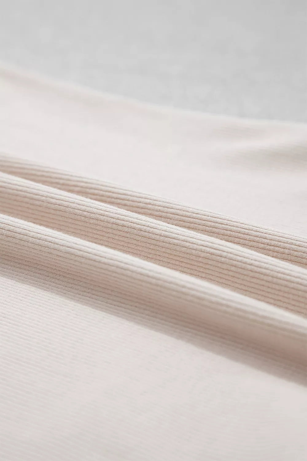 Extreme close-up of fine vertical ribbed texture on soft matte beige fabric