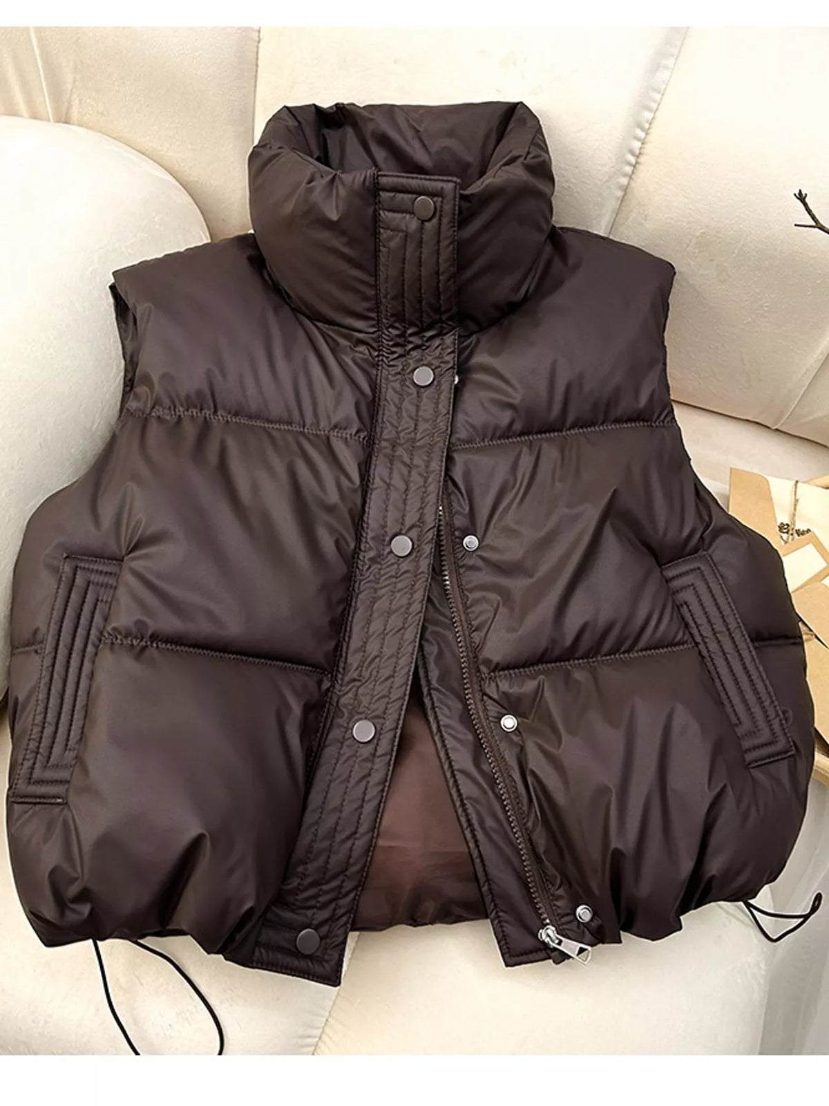 Brown sleeveless coat draped over sofa showing fabric sheen and silhouette