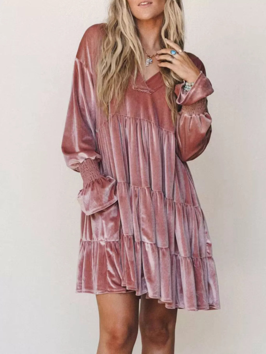 Inquadratura media di un vestito in velluto frangiato color marrone-rosa che evidenzia polsini elastici e texture del tessuto