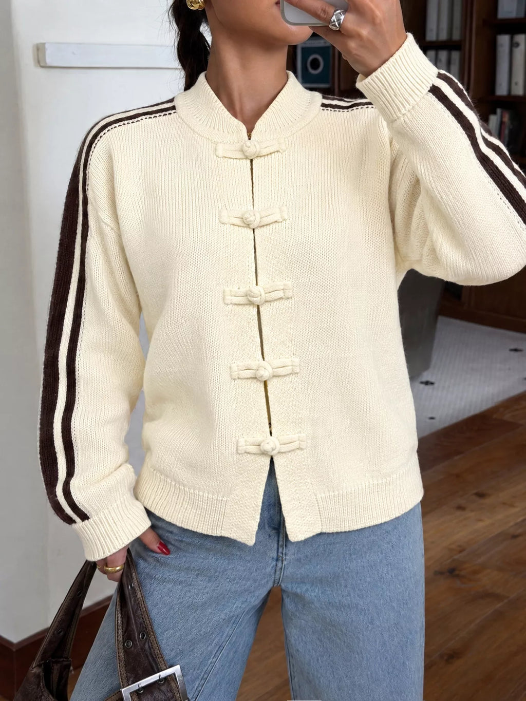Nahaufnahme der cremefarbenen Acryljacke mit traditionellen Knopfverschlüssen und gerippten Bündchen