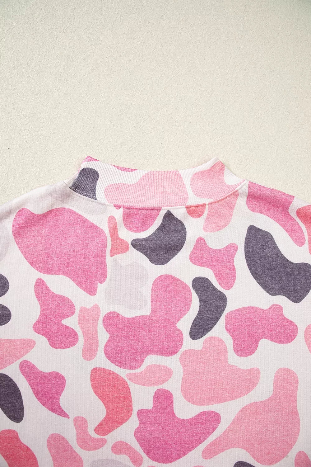 Back view of ribbed mock neck collar laid flat displaying pink dark grey and white pattern