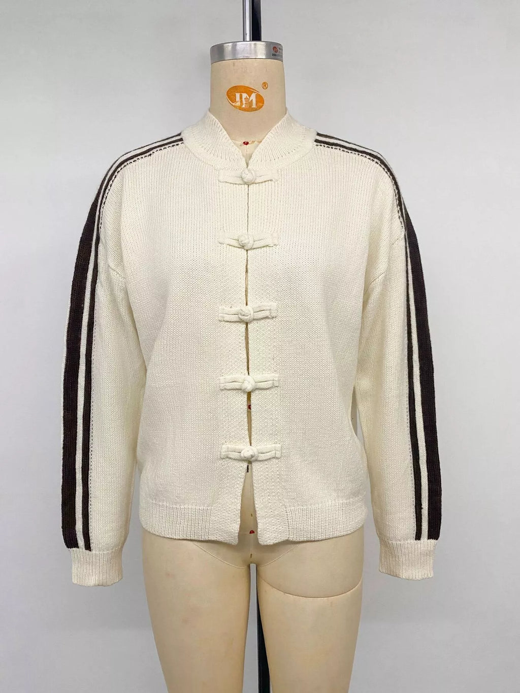 Frontalansicht der elfenbeinfarbenen Jacke am Mannequin mit Stehkragen und traditionellen Knopfverschlüssen