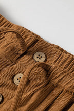 Macro de botones redondos de madera de cuatro agujeros y lazos del cordón en la tapeta frontal de pantalones de pana camel