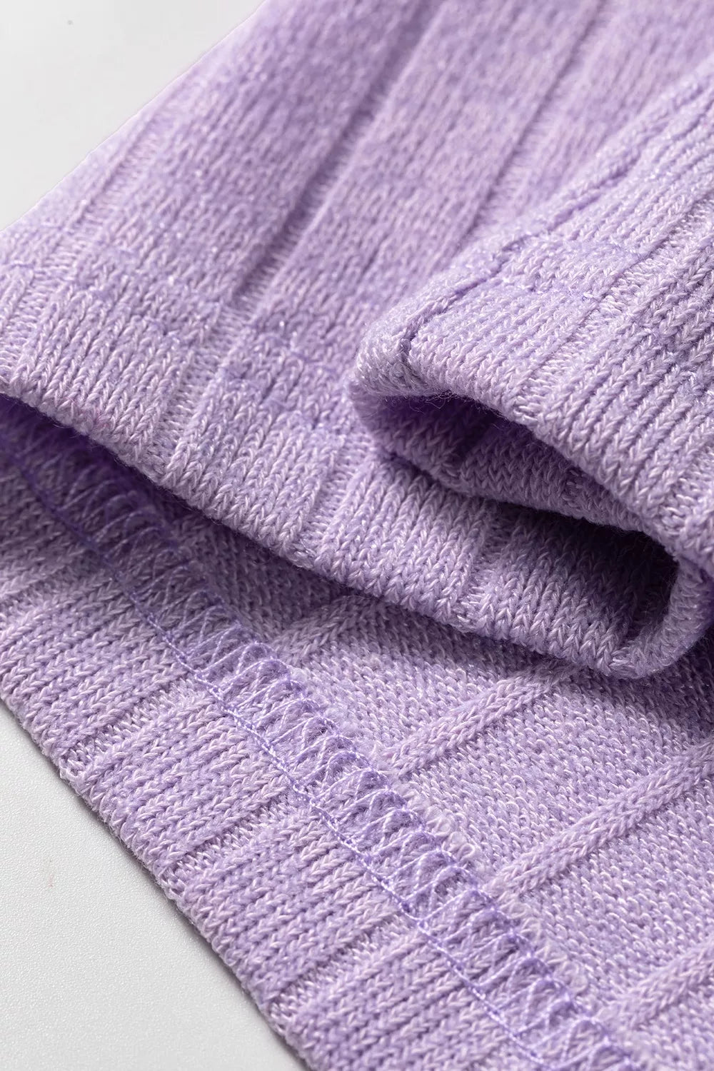 Extreme close-up of folded lavender ribbed knit fabric emphasizing fuzzy texture and stitching
