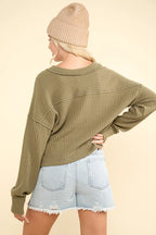 Back view of olive green long sleeve top showing horizontal exposed seam across upper back and straight hemline