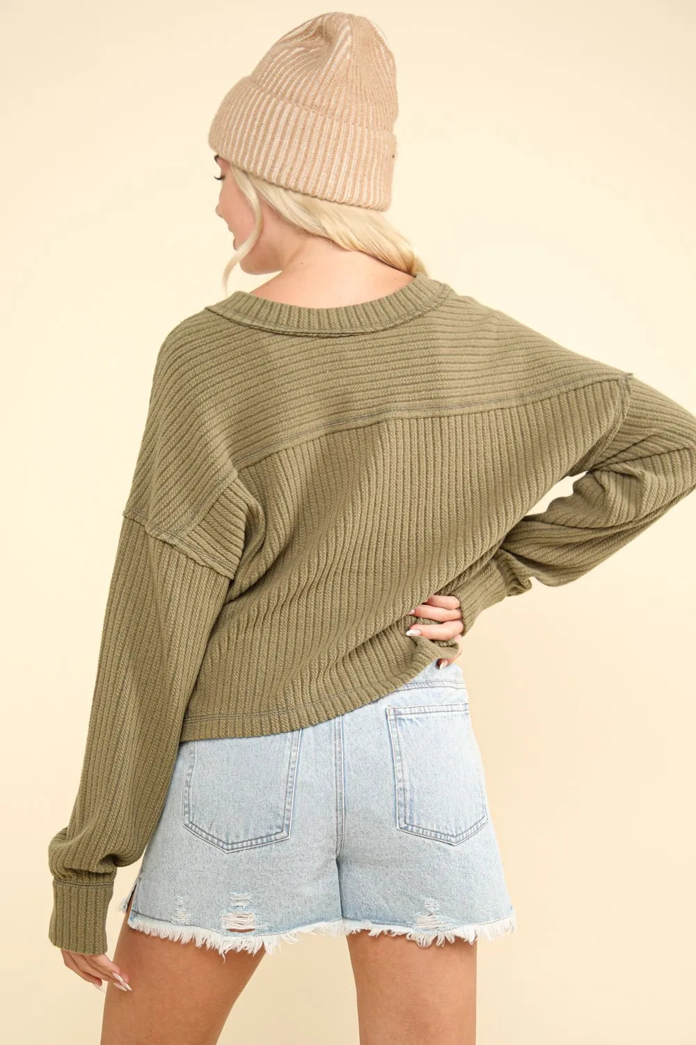 Back view of olive green long sleeve top showing horizontal exposed seam across upper back and straight hemline