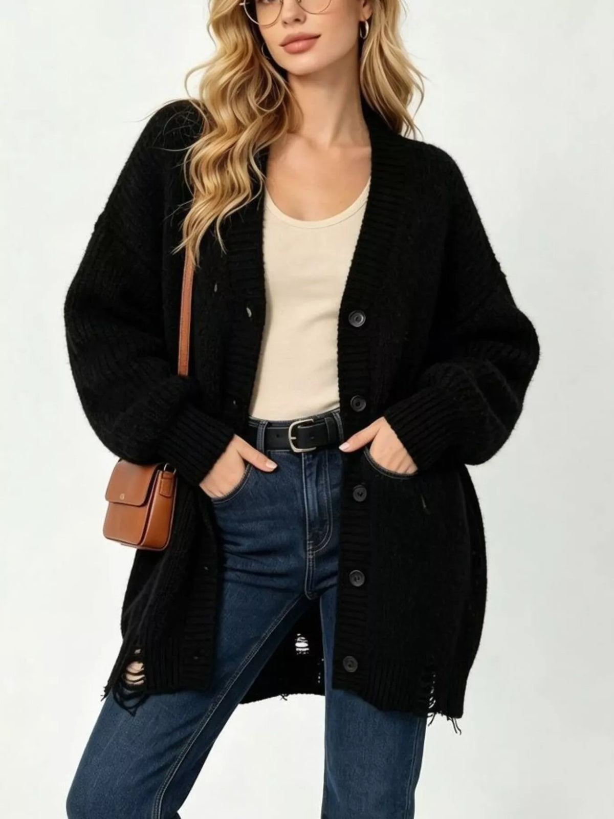 Black oversized cardigan with ripped hem and dark buttons worn by model in jeans