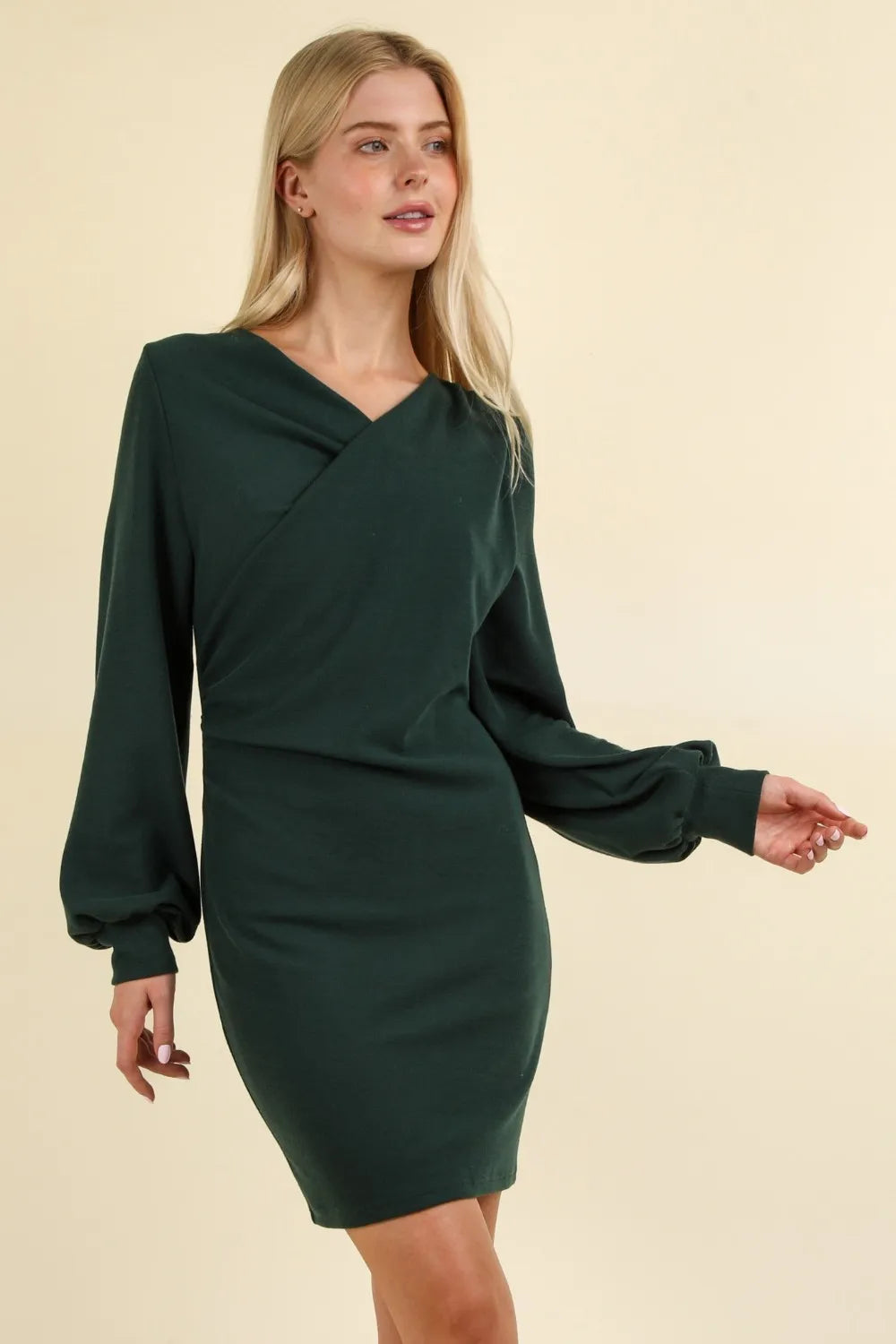 Three-quarter angle of dark green dress displaying wrap-style chest detail