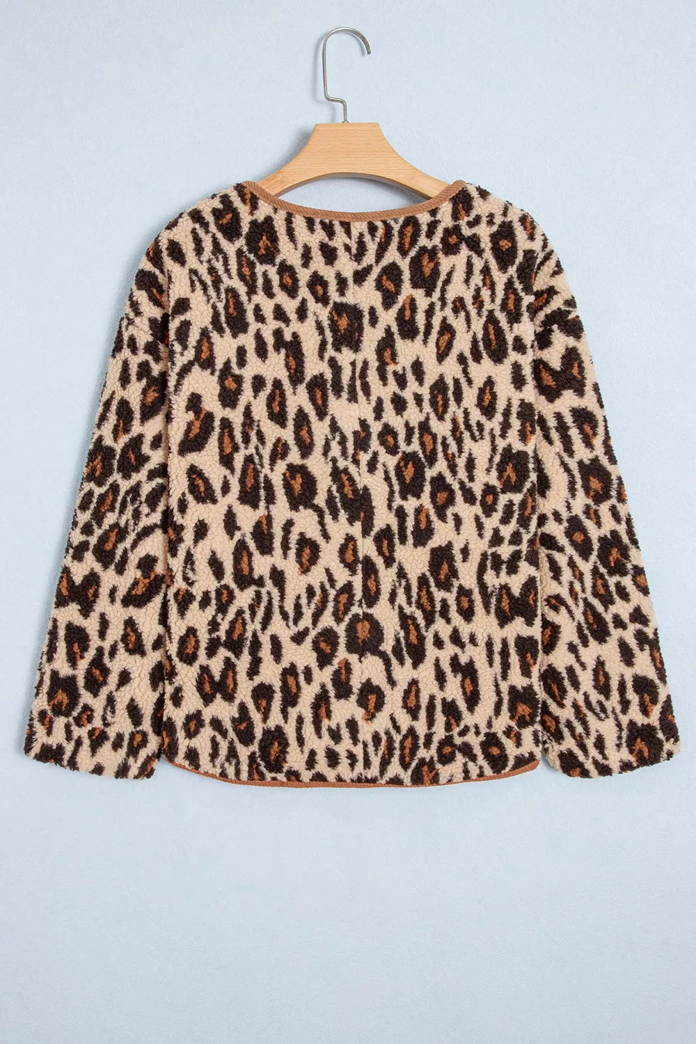 Back view of leopard print jacket on hanger displaying continuous animal print and curved corduroy hem