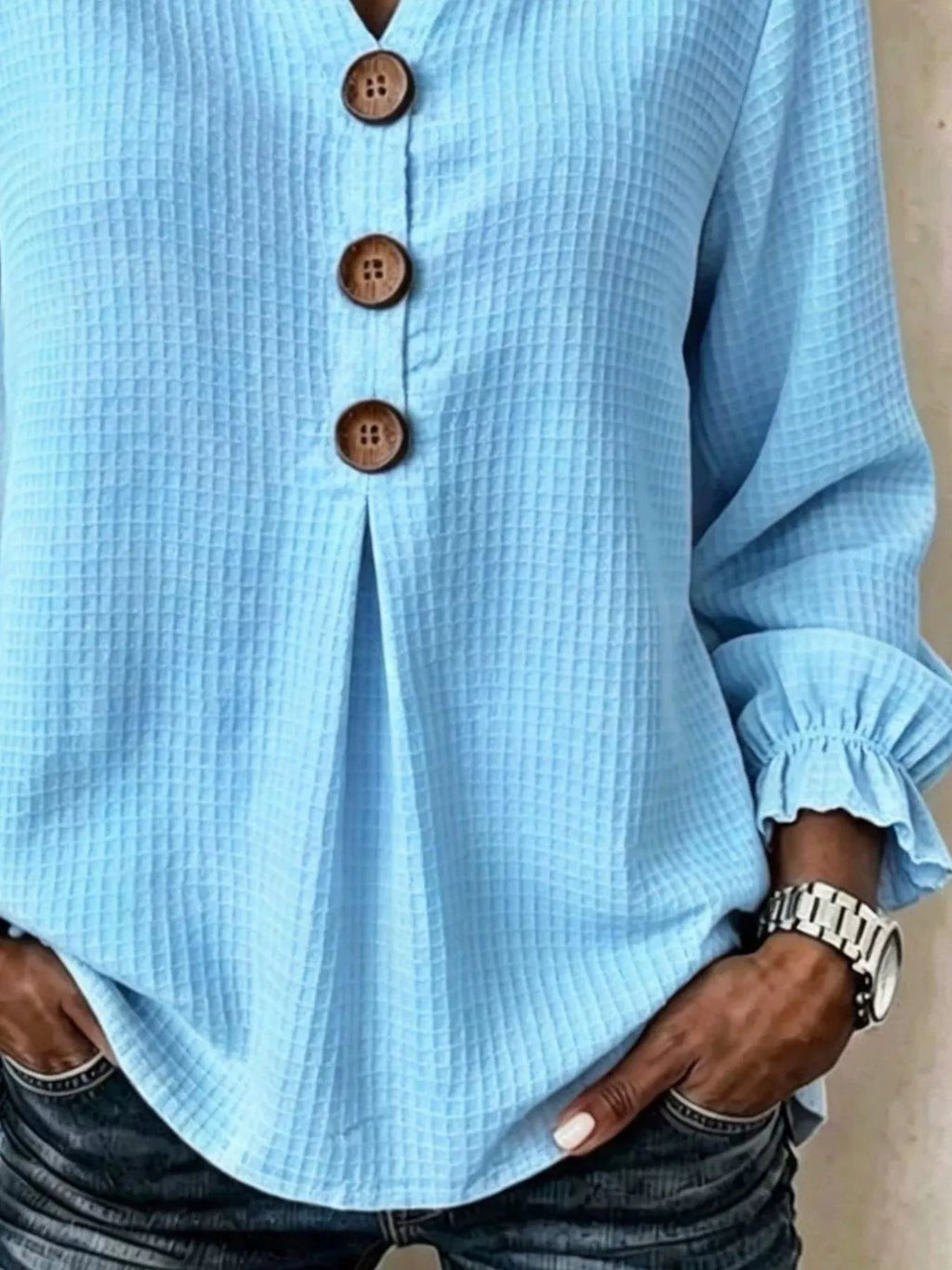 Detalle de la abertura tipo ojo de cerradura de la blusa azul claro y puño fruncido