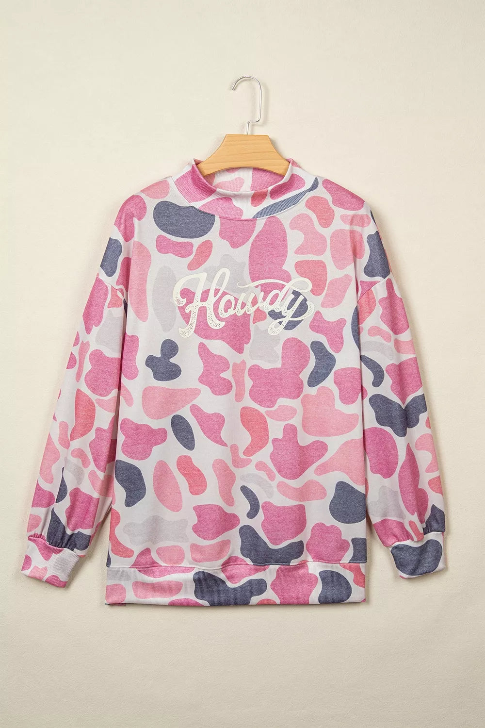 Pink grey camouflage pullover on wooden hanger showing ribbed mock neck and elastic cuffs