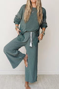 Barfüßiges Model posiert im teal gestreiften Lounge-Set, zeigt fließenden Stoff und oversized Patchwork-Top-Passform