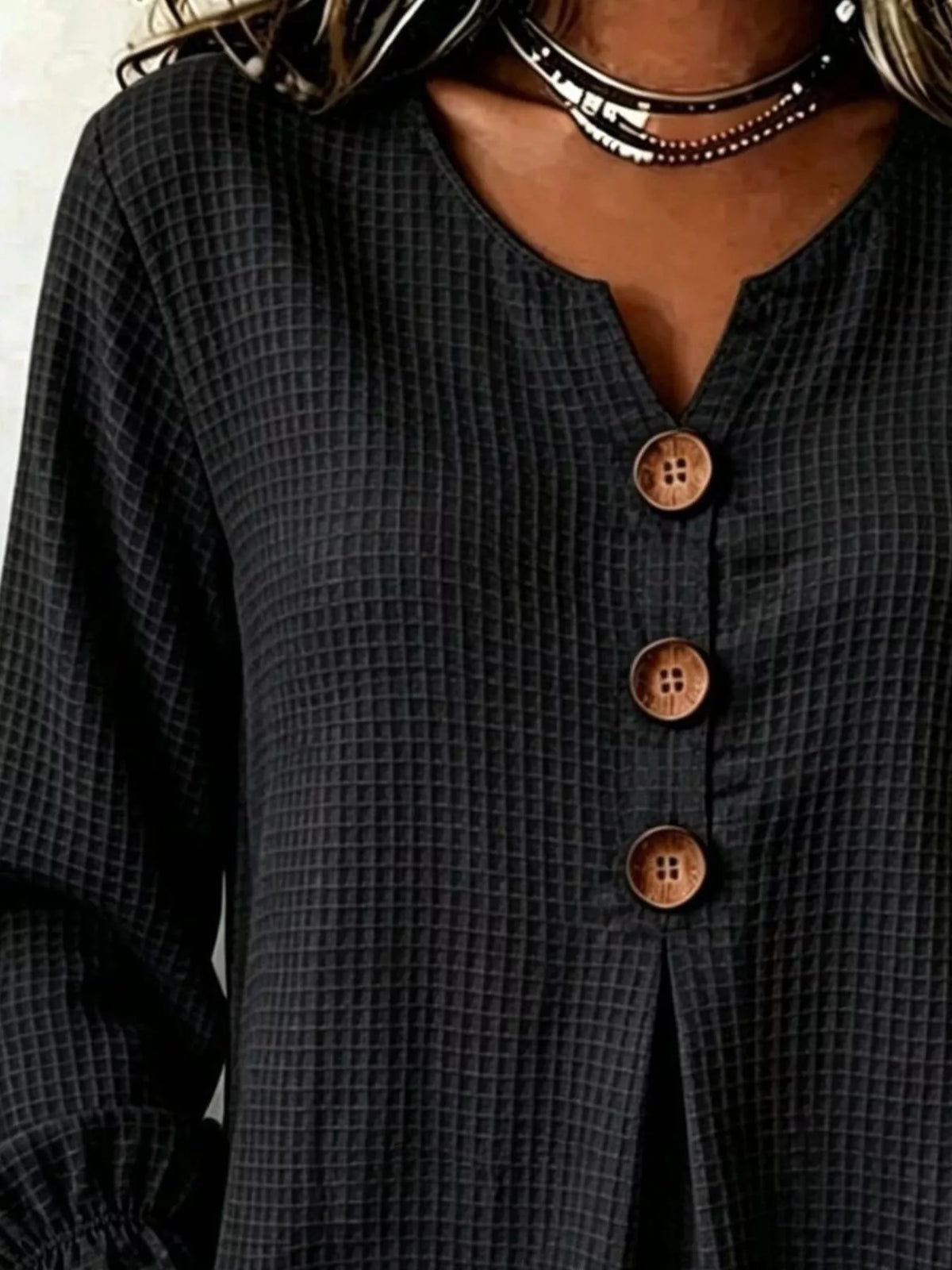 Primer plano de la textura del tejido waffle negro y detalle de los botones marrones
