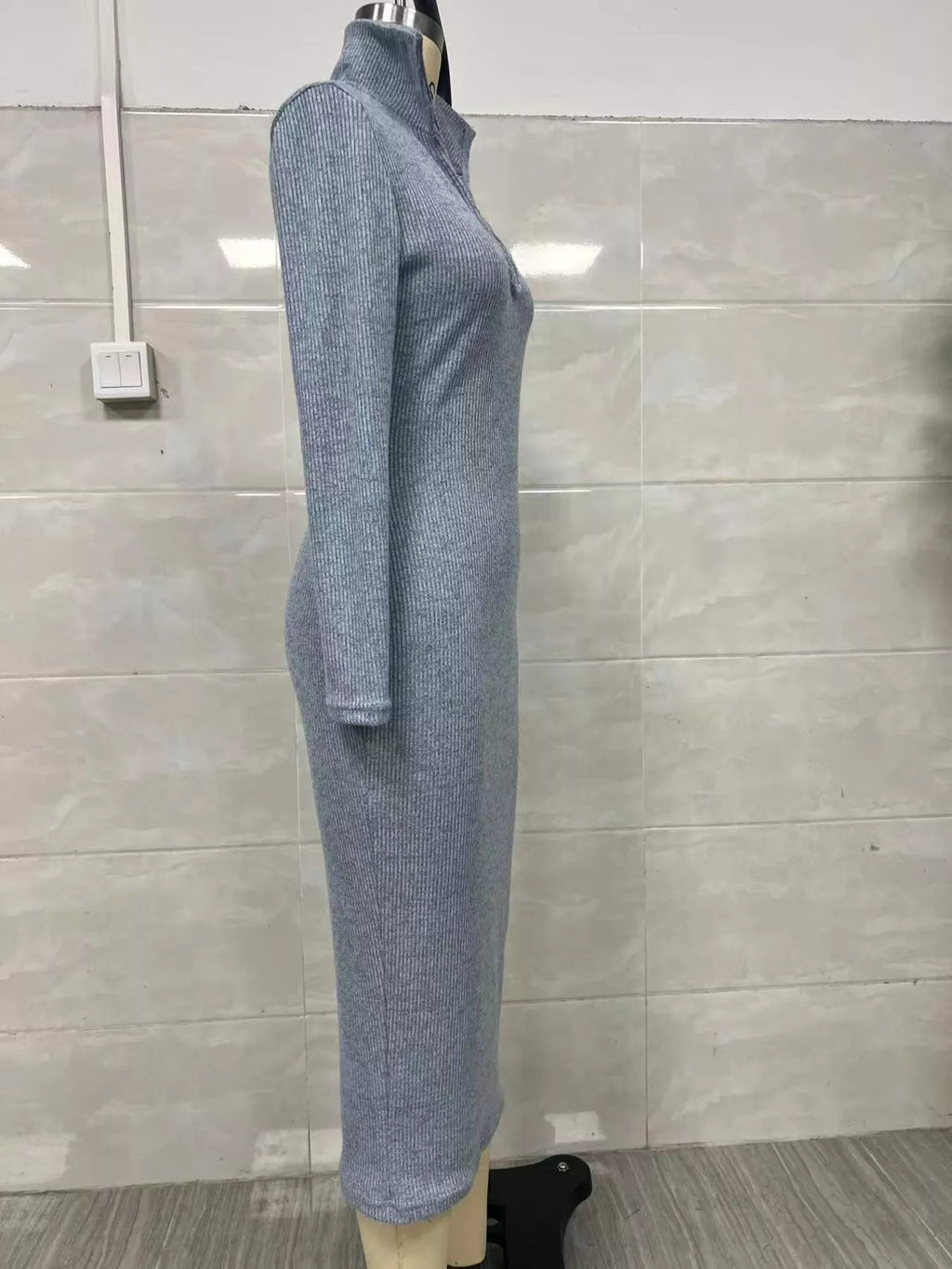 Profil latéral d'une robe tricotée côtelée bleu-gris clair sur mannequin illustrant l'ajustement épousant le corps et le détail du col haut