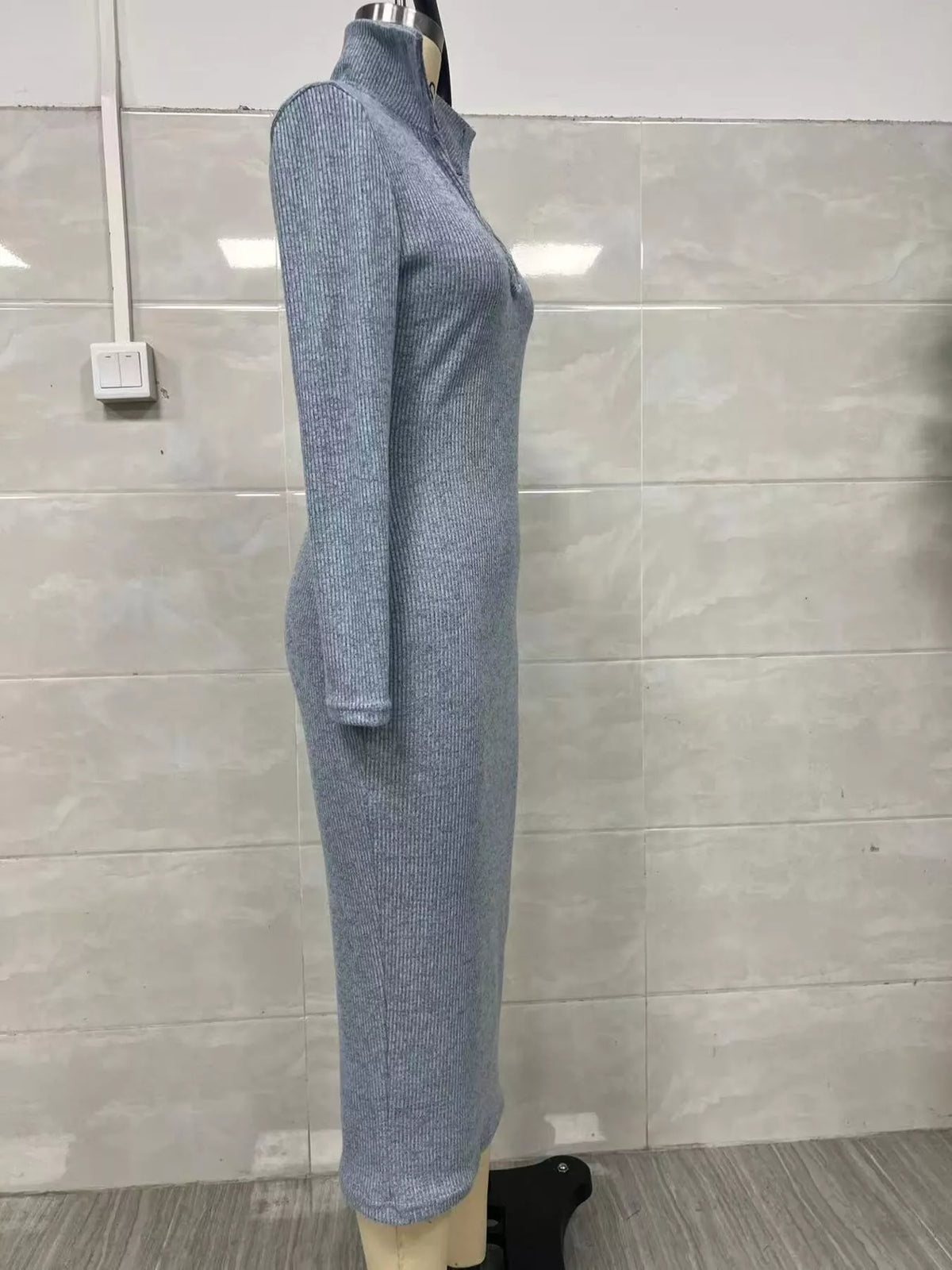 Profil latéral d'une robe tricotée côtelée bleu-gris clair sur mannequin illustrant l'ajustement épousant le corps et le détail du col haut