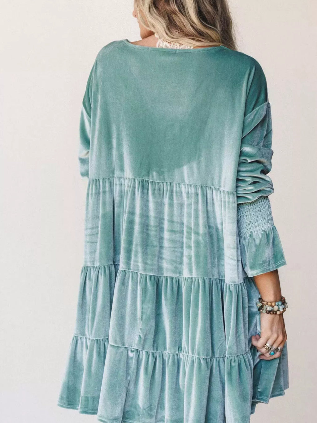 Vista posteriore di una mini dress in velluto verde acqua con gonna a volant a livelli, maniche a palloncino e collo tondo