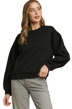Black oversized crewneck sweatshirt with dropped shoulders, ribbed cuffs, and V-shaped pleated neckline detail on a model