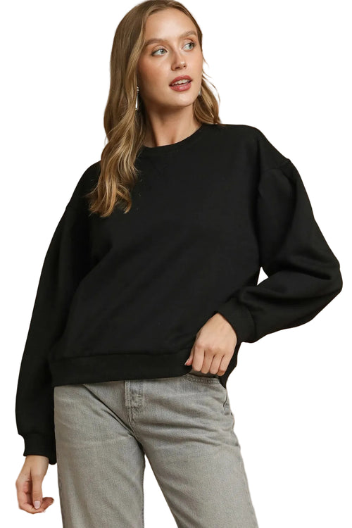 Black oversized crewneck sweatshirt with dropped shoulders, ribbed cuffs, and V-shaped pleated neckline detail on a model