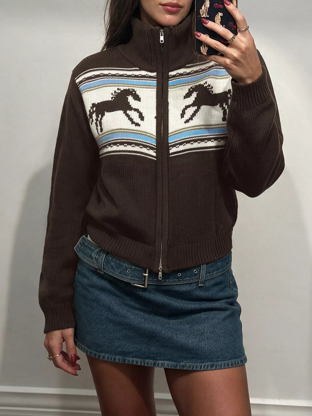 Braune Strickjacke mit hohem Mock-Neck, gerippten Bündchen und Pferdemotiv auf der Brust, kombiniert mit einem Denim-Rock