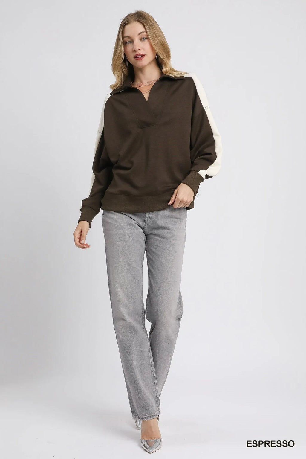 Full outfit styling of oversized brown cream polo tucked into grey jeans with silver heels