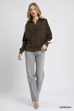 Full outfit styling of oversized brown cream polo tucked into grey jeans with silver heels