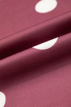 Macro view of smooth burgundy polyester knit fabric surface with large white circular dot pattern