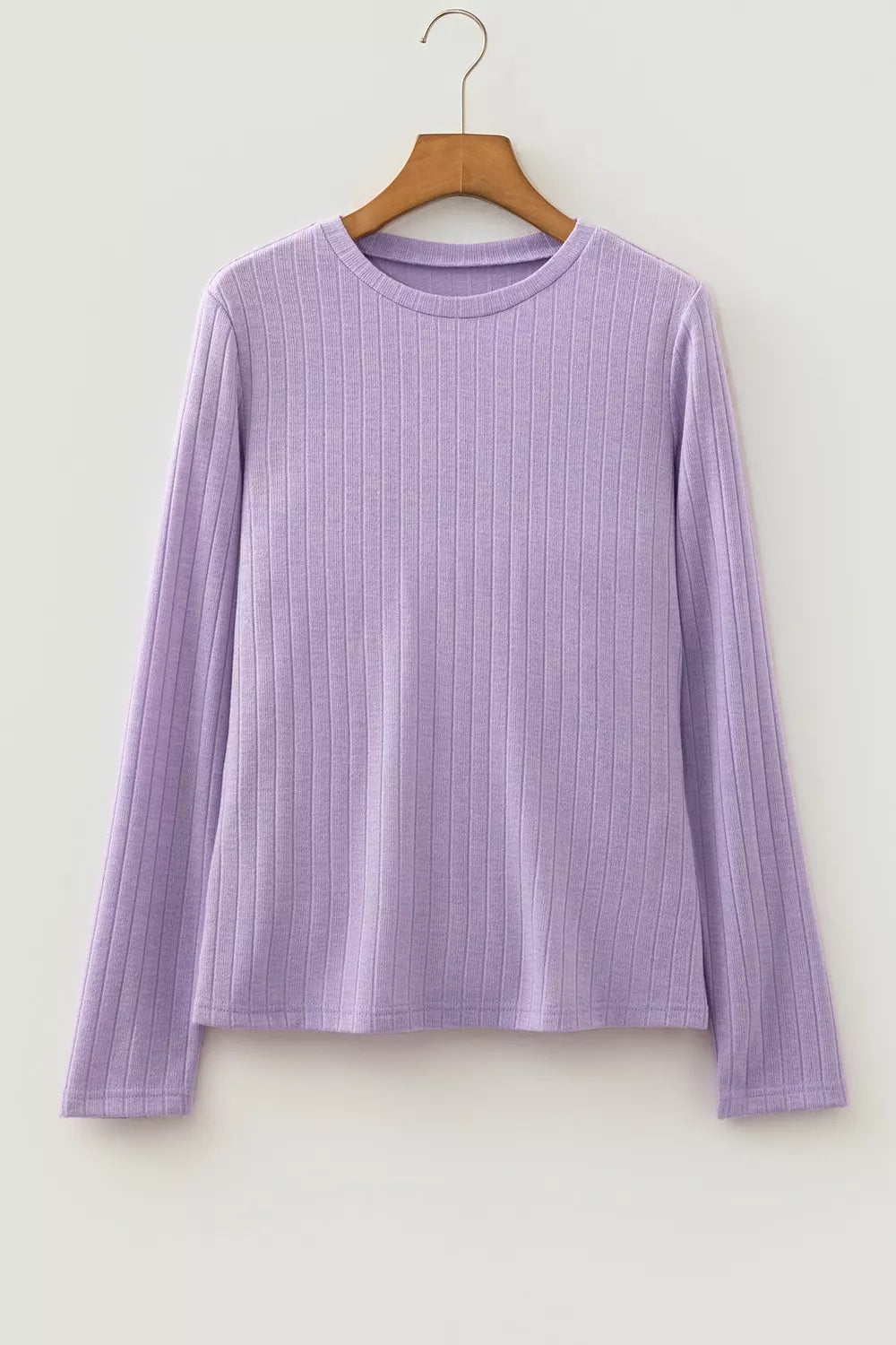 Light lavender ribbed knit top hanging on wooden hanger against white background showing round neck