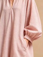 Vue de profil de la robe rose poudré mettant en valeur la manche ballon volumineuse et la main dans la poche fonctionnelle