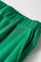 Detalle de cintura elástica verde esmeralda y bolsillo lateral en tela de algodón mezclado suave. Cómodo y práctico.