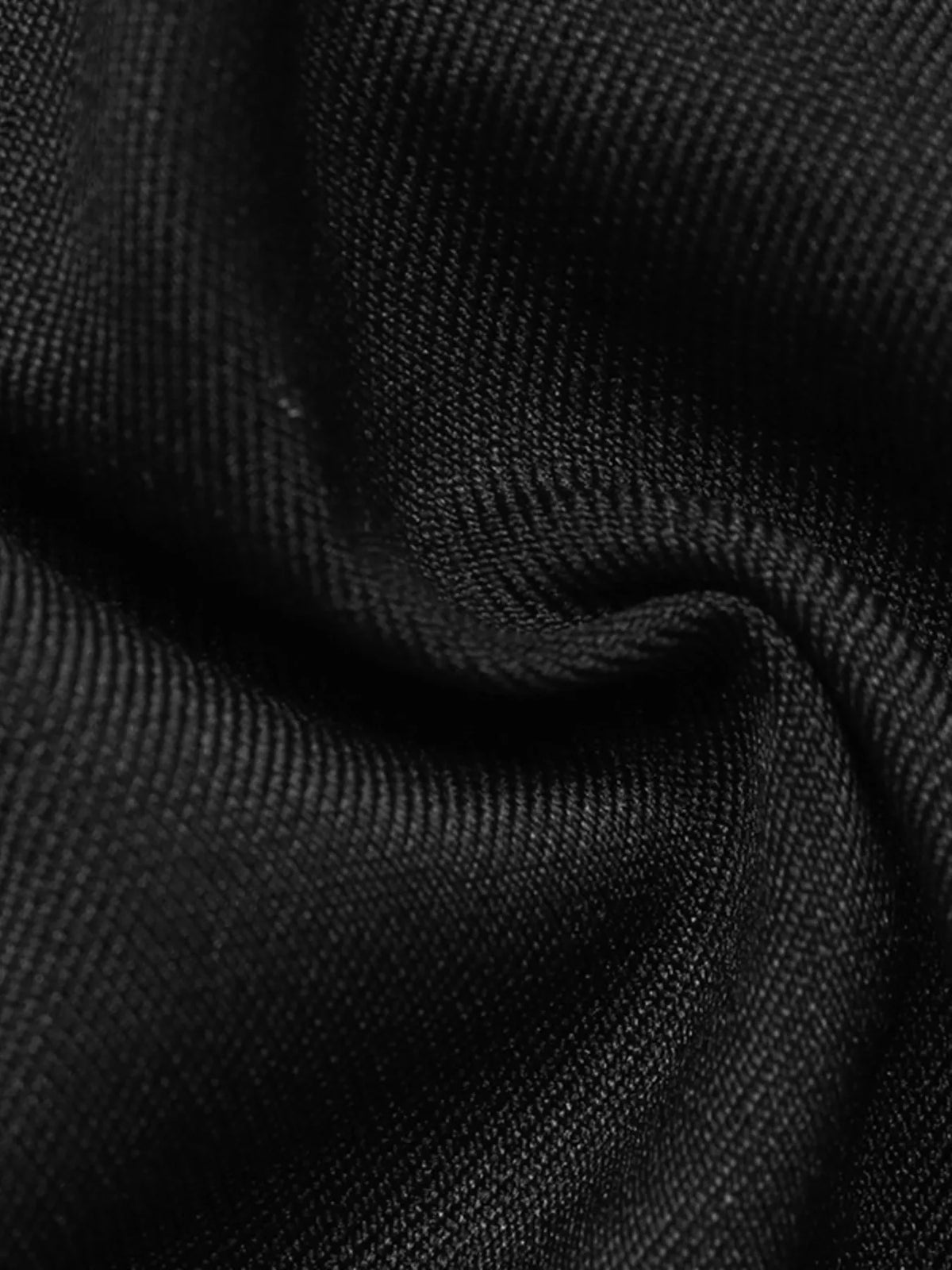 Extreme close-up of fine tight synthetic weave with subtle sheen on black fabric