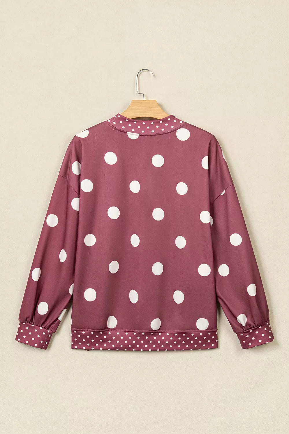 Back view of maroon polka dot sweatshirt on hanger displaying continuous large dot print design